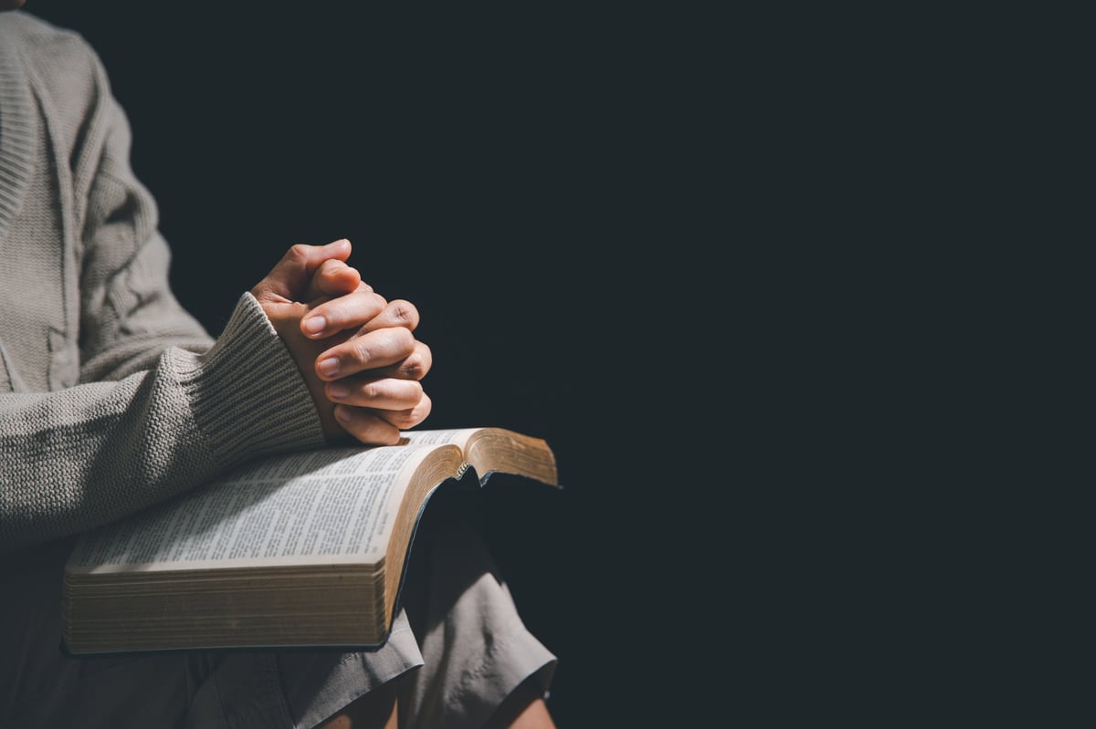 Mujer orando a Dios con la Biblia en las manos